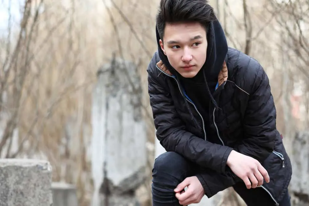 The Best K-Pop Hairstyles for Korean Guys (Plus Styling Tips) 10 A man outdoors in the cold weather wearing a bowl-cut hairstyle with hair on top and short fade-sides.