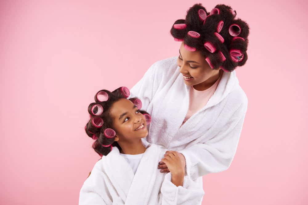 A beautiful mother and daughter wearing foam hair rollers to create voluminous curls without using a curling iron.