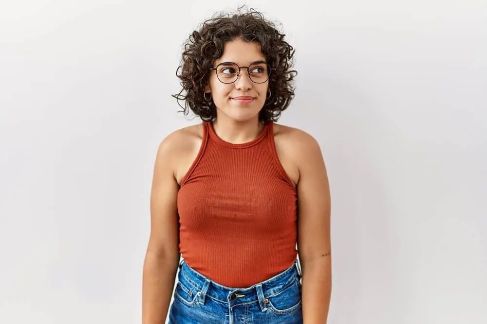 Do Mexicans Have Curly Hair? Is Curly Hair Common in Mexico? 6 A stylish Hispanic female wearing cute eyeglasses styled her hair with moisturizing hair products for curly girls.