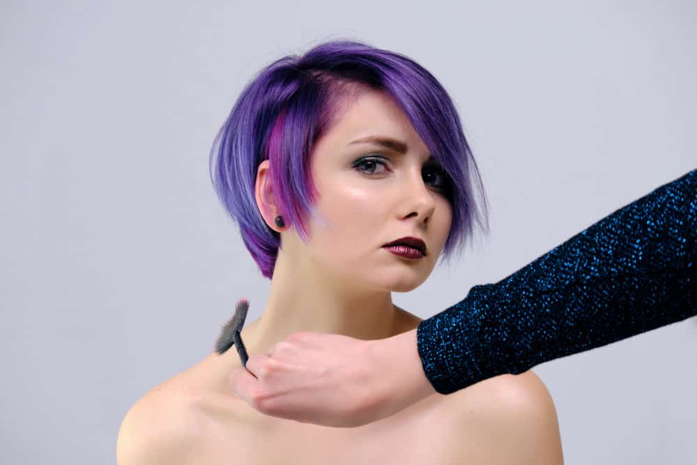 A girl representing the bisexual flag wearing a new haircut that stops at jaw level with a traditionally long bang.