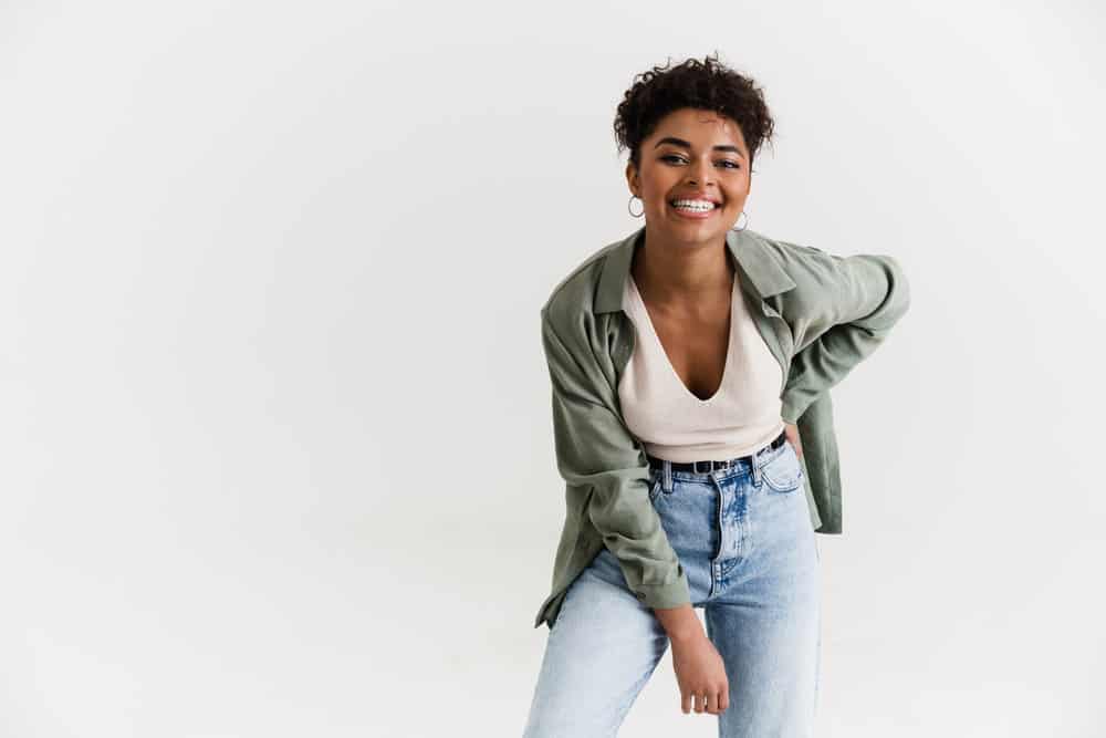 A black girl is wearing a casual outfit and laughing during a playful time with family and friends.