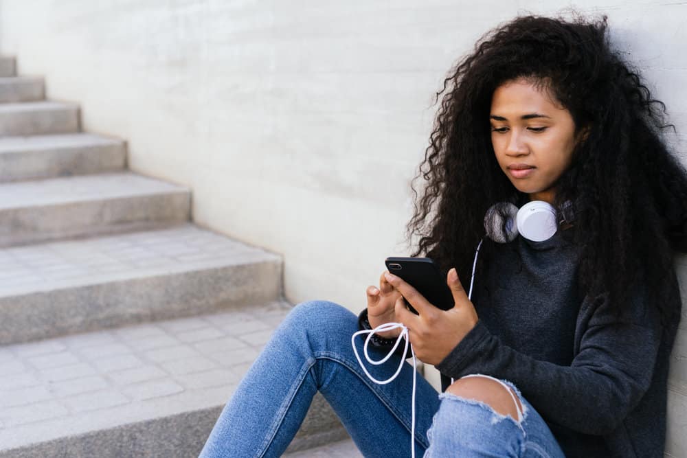 A beautiful female with wavy and curly hair strands on her dark brown natural hair is wearing a casual outfit.