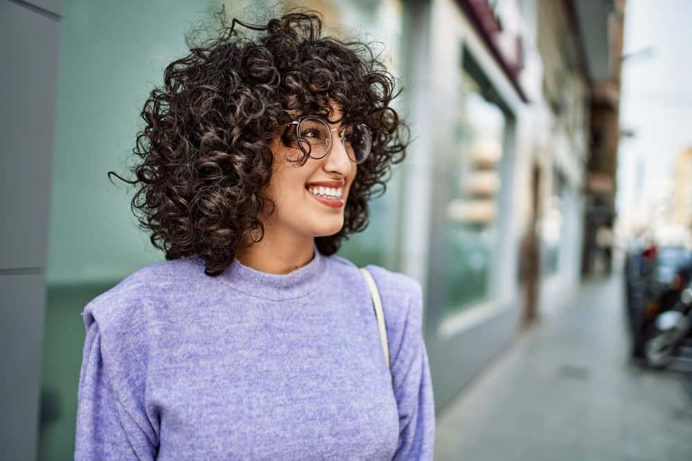 Young middle east lady with naturally curly hair texture with loose hairs (or a few flyaways) that are untamed.