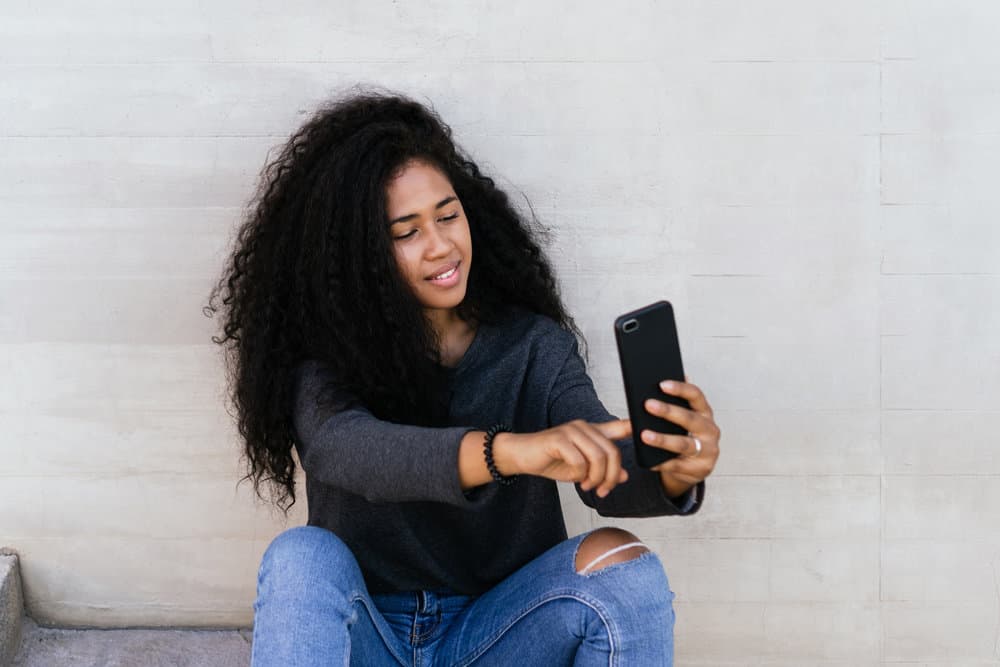 A young African American female with fine hair takes a selfie after experiencing hair texture changes.