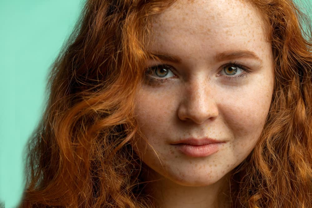 Close-up of a female with type 2A hair strands that uses argan oil within her hair care routine to fix damaged hair.