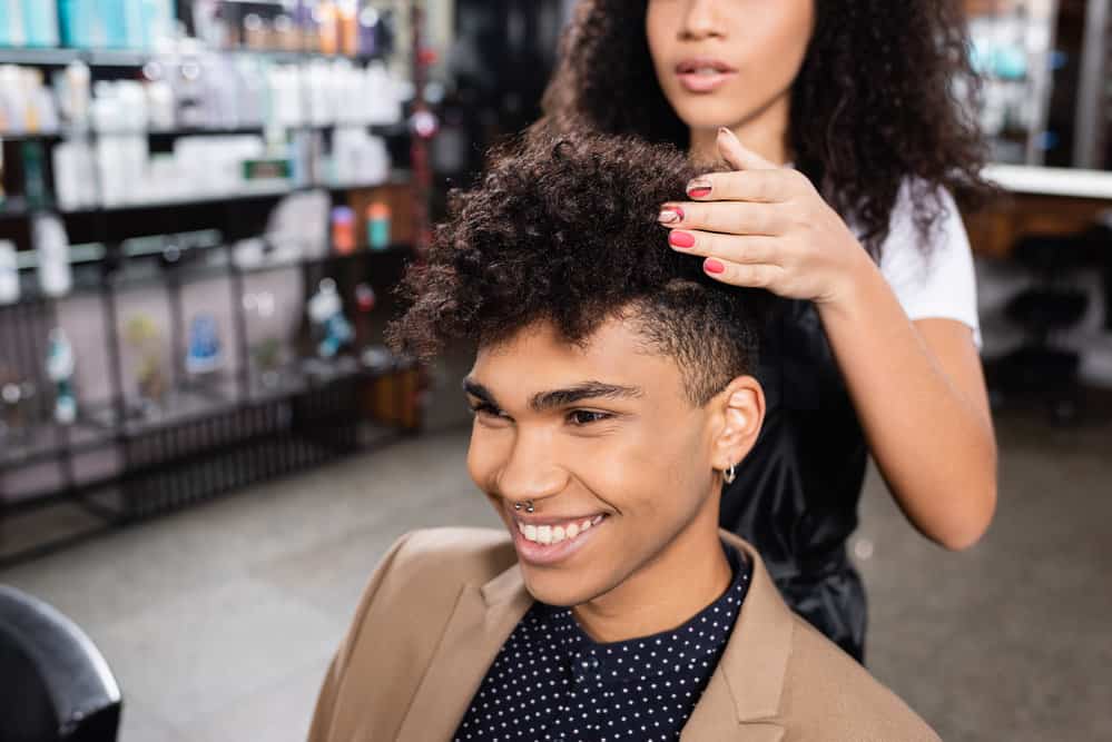 A black man is getting a haircut and wondering how much to tip your hairdresser during the holiday season.