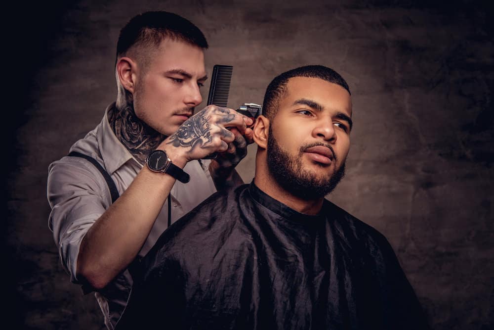 A man getting a proper men's haircut from a professional hairstylist after a shampoo and hot towel treatment.