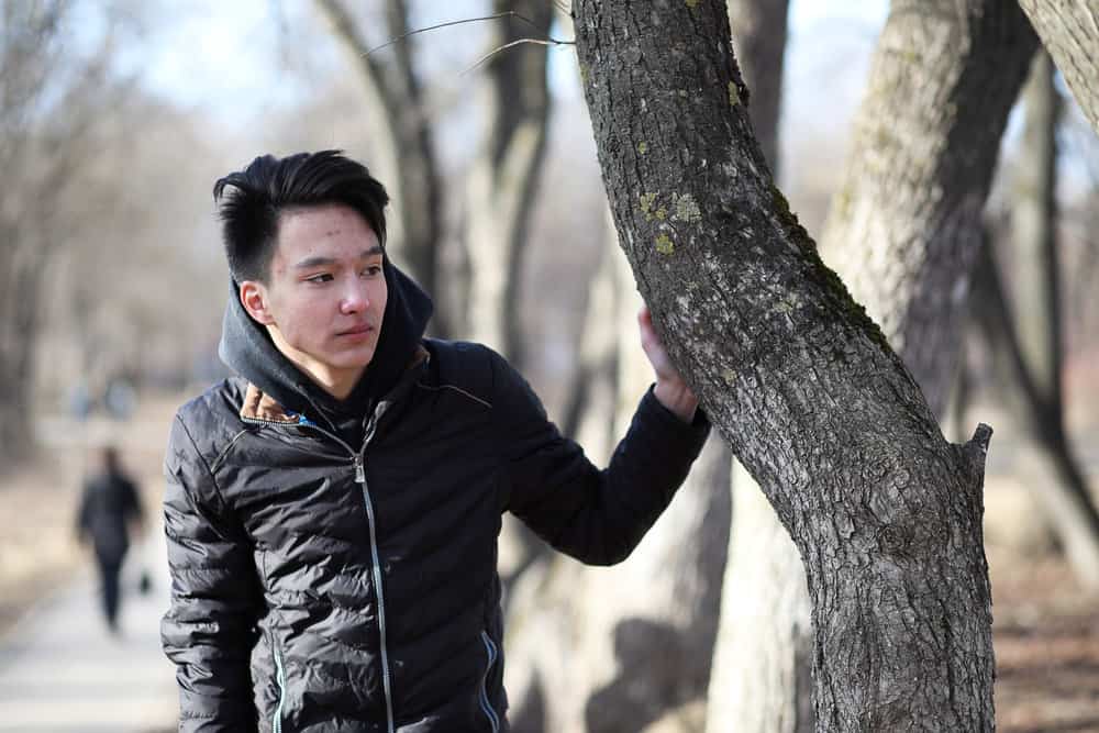 The Best K-Pop Hairstyles for Korean Guys (Plus Styling Tips) 15 A young male wearing a style that is popular among Korean men has bleached hair that was later dyed dark brown.