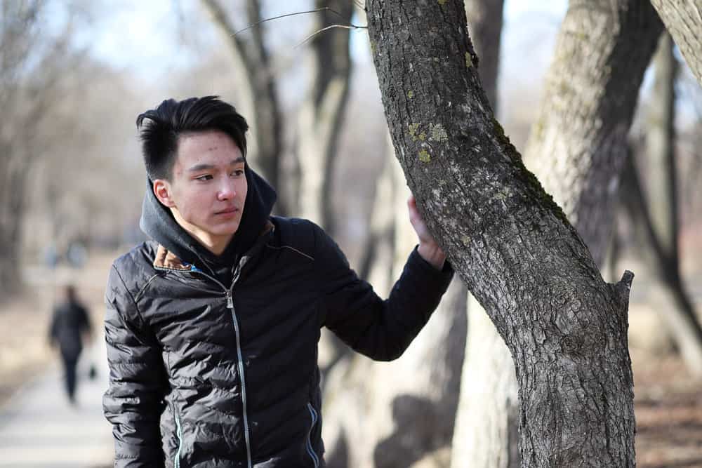 A young male wearing a style that is popular among Korean men has bleached hair that was later dyed dark brown.