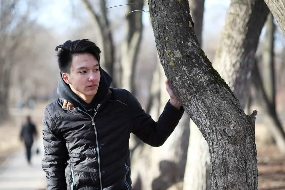 The Best K-Pop Hairstyles for Korean Guys (Plus Styling Tips) 15 A young male wearing a style that is popular among Korean men has bleached hair that was later dyed dark brown.