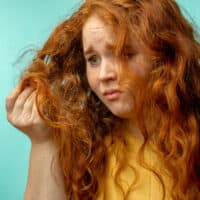 A white girl with red hair sporting a yellow shirt with brittle hair containing visible split ends and frizz.