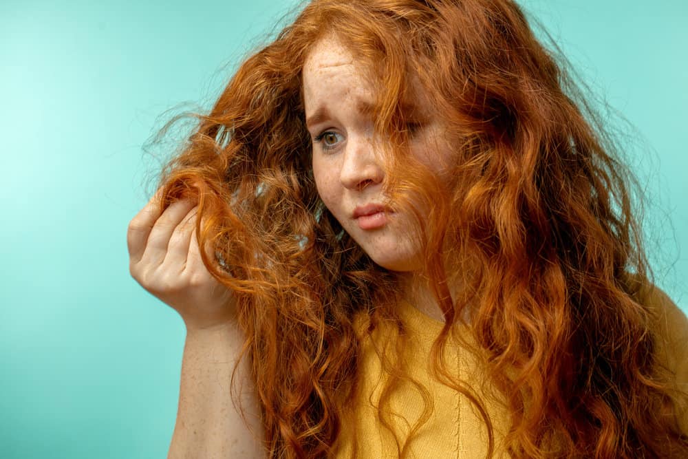 A white girl with red hair sporting a yellow shirt with brittle hair containing visible split ends and frizz.