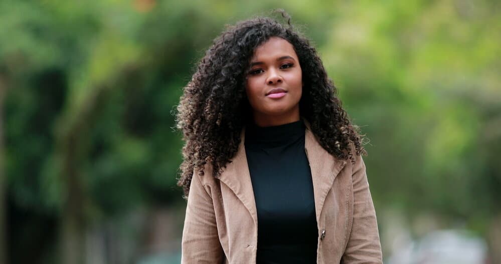 A confident black female with towel-dried hair used a conditioning treatment to build healthier hair strands.