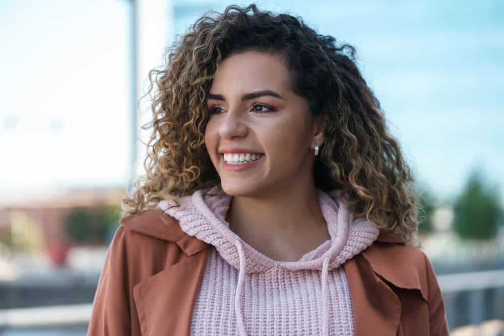 A lady with slightly wet hair following a rainstorm is wearing a casual outfit with beautiful silver earrings.