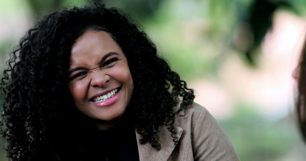 A black girl with shoulder-length hair is wearing human hair extensions adding excess weight to her thicker hair.