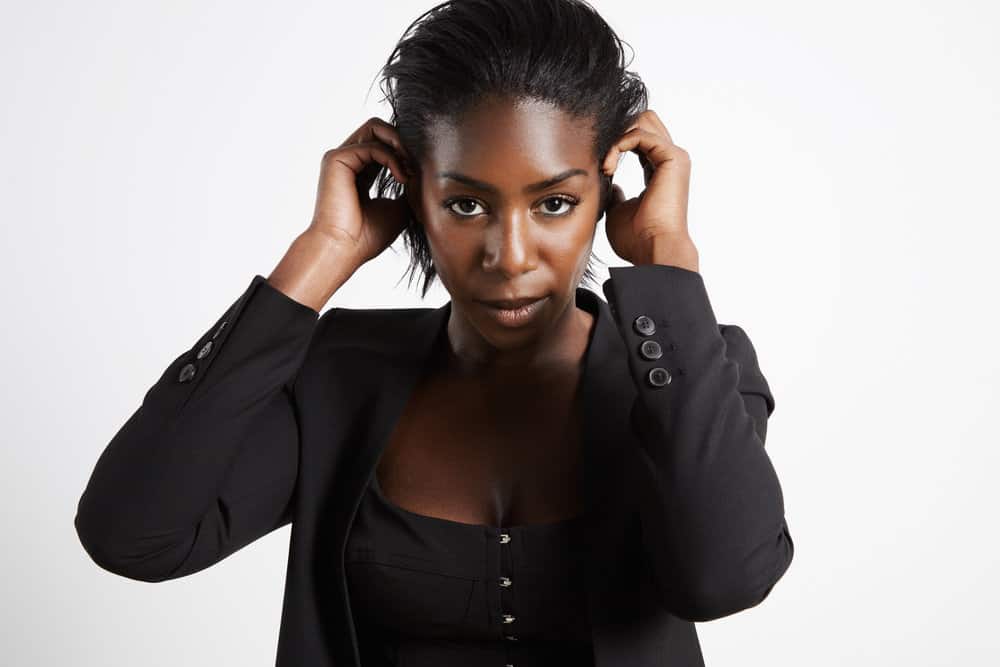 After blow-drying her wet hair, a black businesswoman is wearing a straight-back style as she gets ready for work.