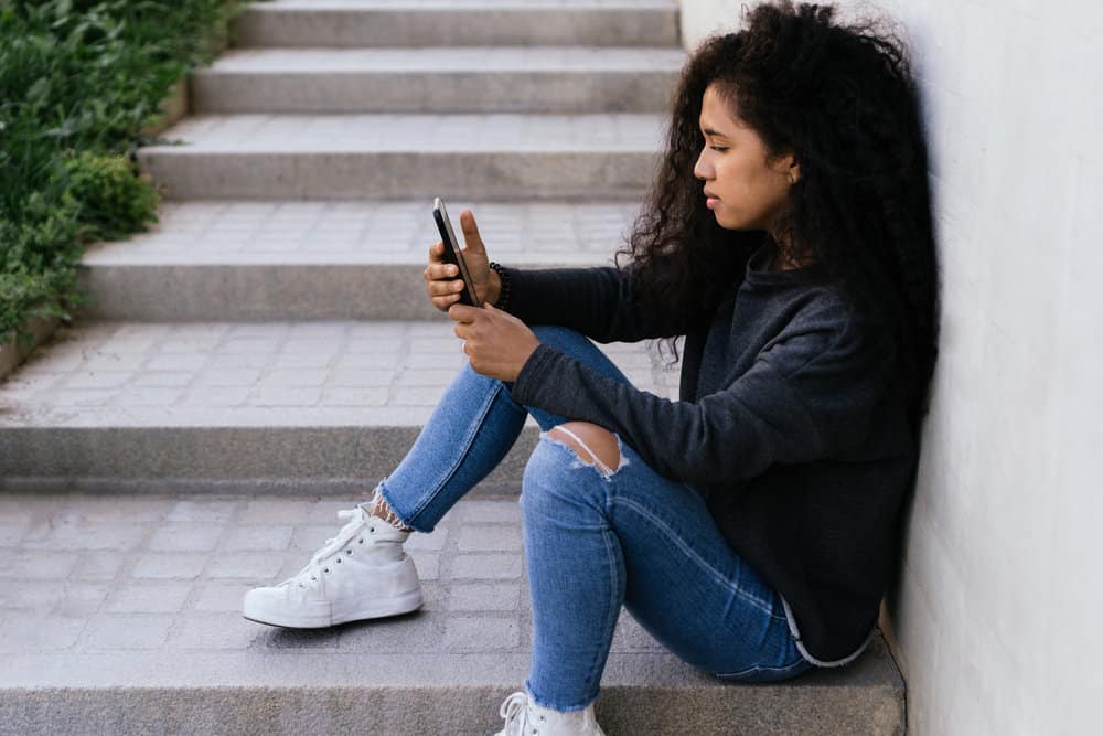 A gorgeous African American female with aging curly hair is researching thinning hair health factors online.