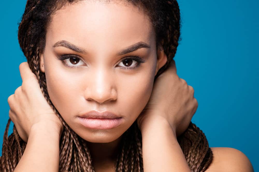 African American female with brown eyes wearing thick tribal braids on her traditional afro hair texture.