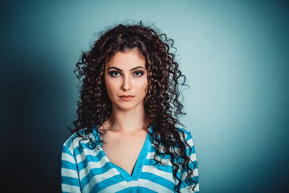 A female with bouncy waves created with two socks is wearing a casual blue and white striped shirt. 