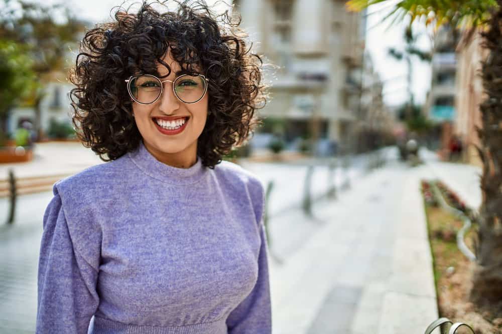 A cute middle eastern female with static hair after trying to tame flyaway hair is wearing a beautiful purple dress.