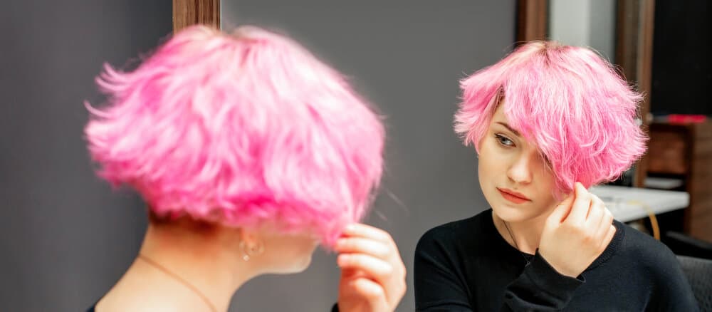 Beautiful young caucasian lady admiring her new hairdo after using hydrogen peroxide to remove tough hair dye stains.