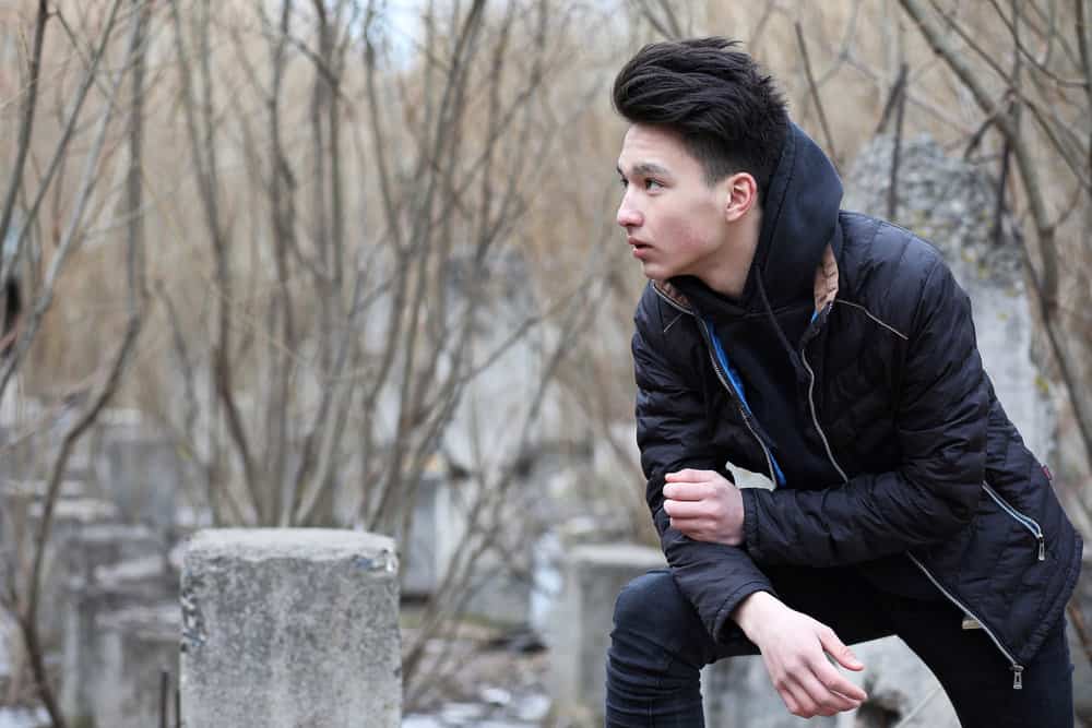 The Best K-Pop Hairstyles for Korean Guys (Plus Styling Tips) 7 Asian man outside wearing a Kpop-inspired style with a buzz cut on the side and extra length on top.