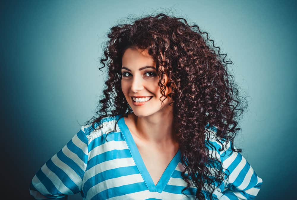 A joyful white girl with tighter curls and a type 1 straight hair natural texture created tight curls by sock curling.