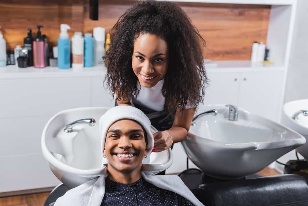 A black man that's a client, and African American stylist are preparing for a full-service haircut and shave treatment.