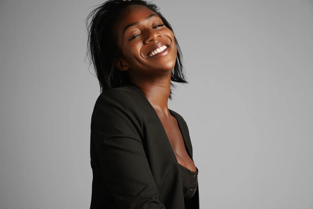 A black girl with beautiful brown skin wearing a normal hair style with straight hair strands in a shoulder-length style.