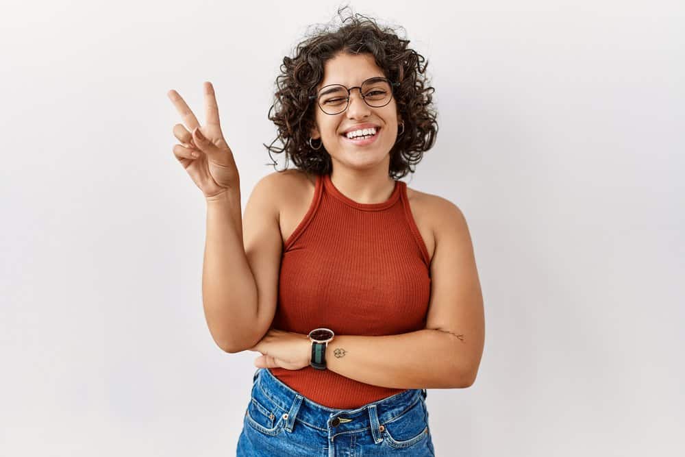 A playful young Mexican female wearing a casual outfit styled her curly textured hair without excessive heat.