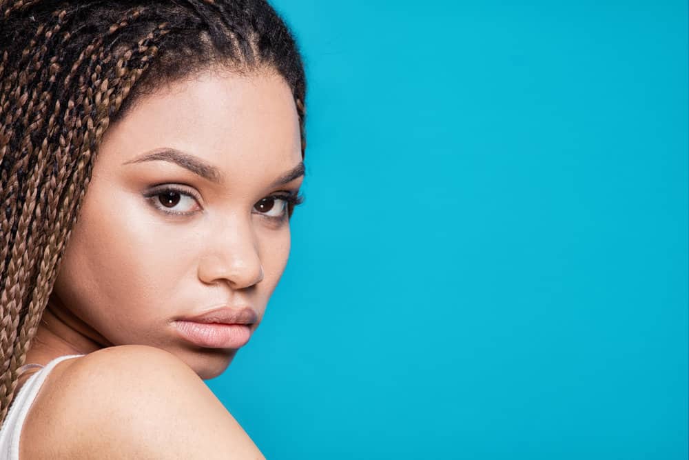 A light-skinned African American female is wearing long tribal braids with skinny, blonde braided strands.