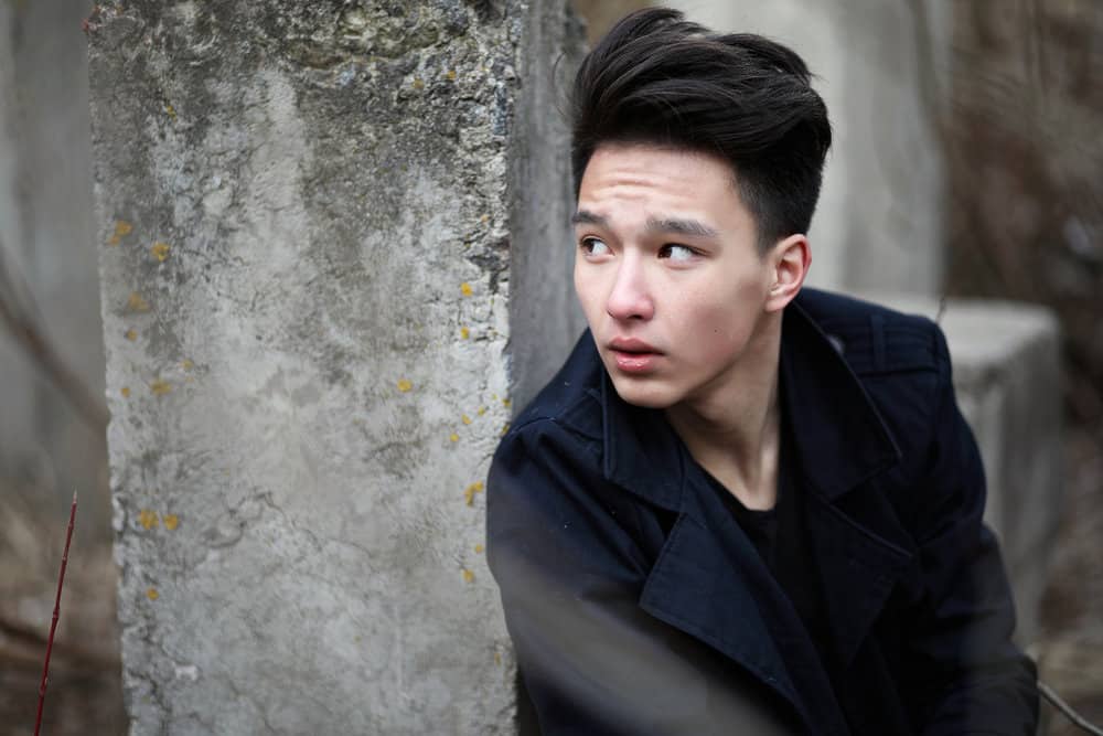 Asian male with medium-length dark hair wearing one of the most popular Kpop hairstyles clipped short on the sides.