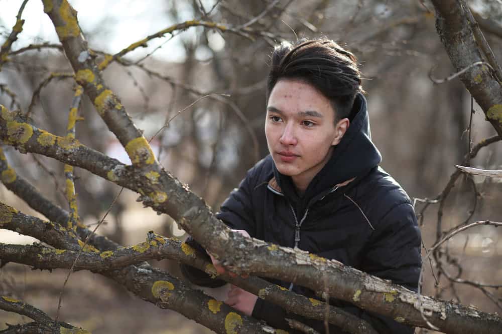 Asian man with a great hairstyle wearing one of the most popular Korean haircuts with a neat side part on the right.