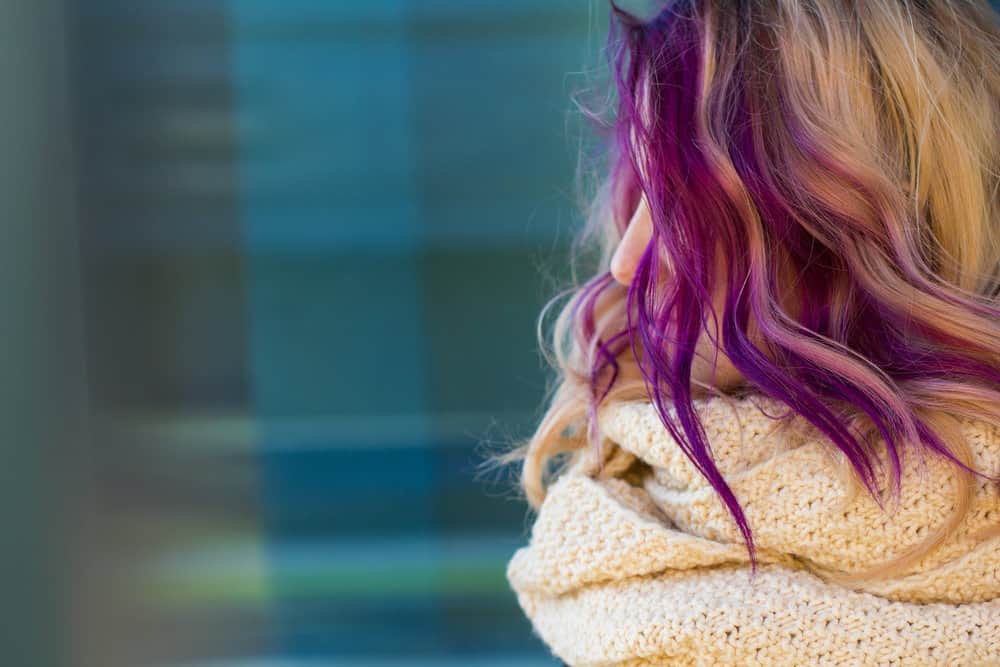 A white lady sitting outside wearing a beige blanket used a DIY hair dye kit and ended up with hair-dyed skin.