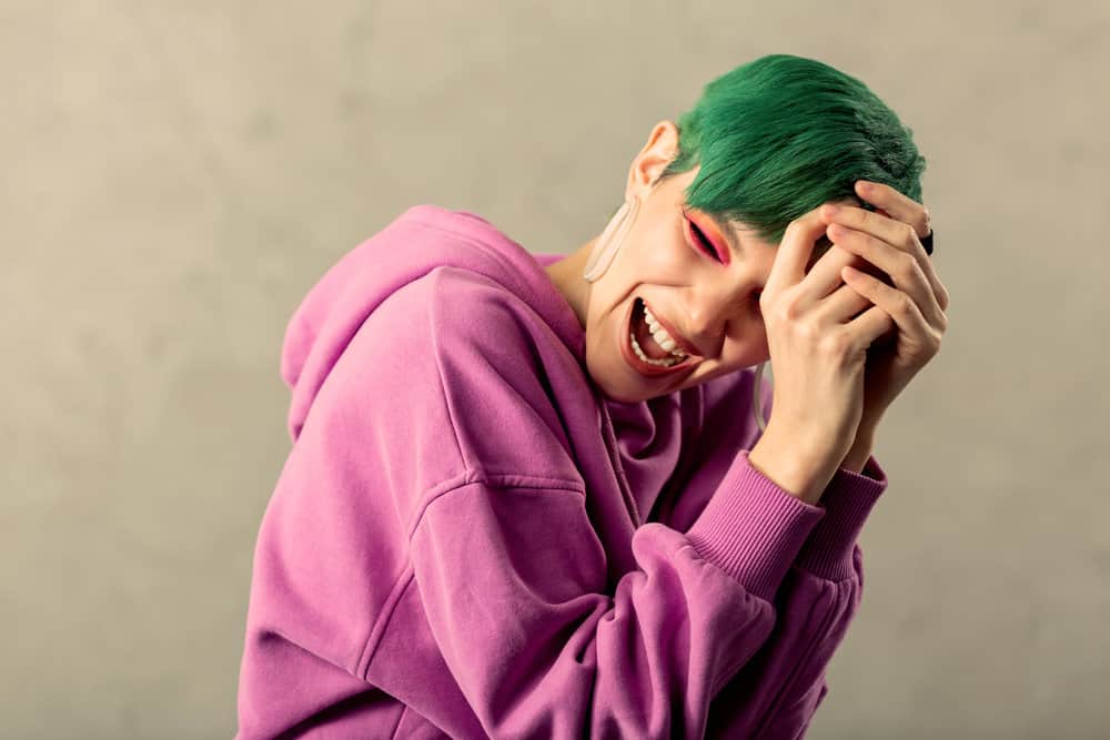 A delighted lady colored her hair green with semi-permanent hair dye - much darker than her natural hair color.