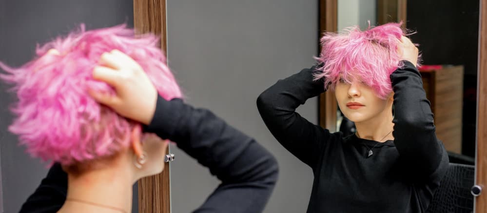 A young female checking out her new hairstyle after using Bar Keepers Friend and a soft scrub brush to clean her sink.