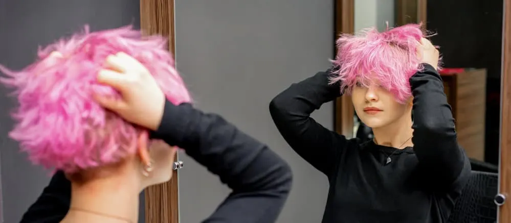 How to Remove Hair Dye From a Sink & Counter: Step-By-Step 13 A young female checking out her new hairstyle after using Bar Keepers Friend and a soft scrub brush to clean her sink.