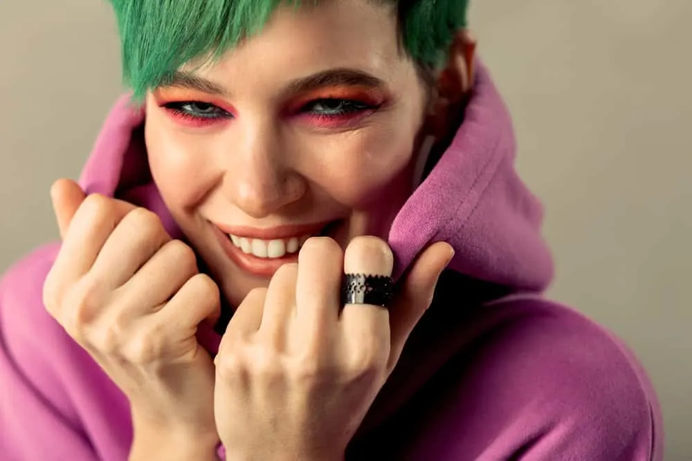 Fading Green Hair: How to Fade Green Dye Fast Step-By-Step 8 A cute woman with sincere emotions used hair bleach to remove blue dye before applying green dyes.