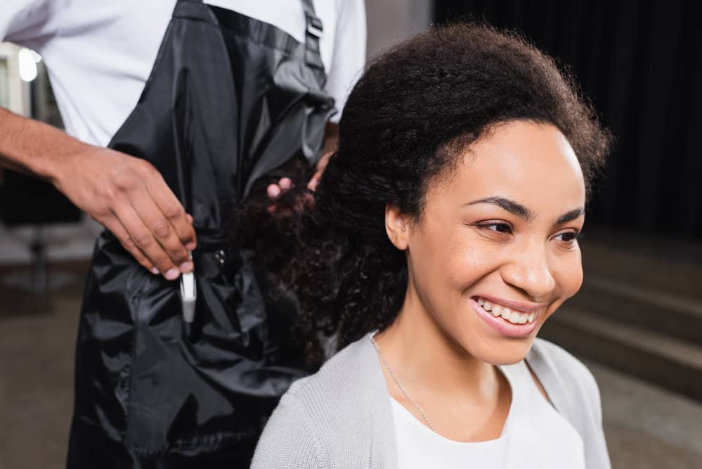 African American female with frizzy type 3 hair strands is starting a hair appointment at a local hair salon.