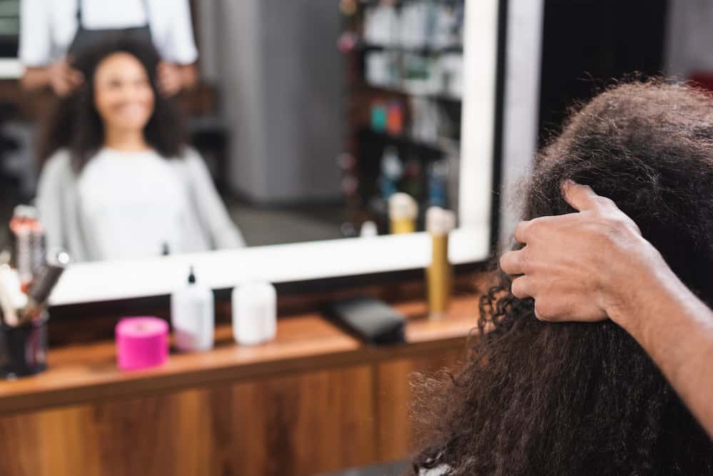 An African American female that's finishing up an appointment to have her hair dyed by a professional colorist.