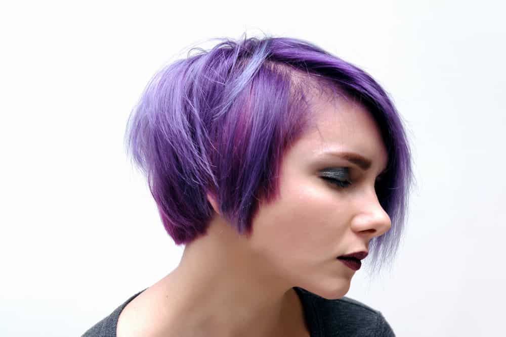 A bi-woman wearing her hair long in the front and short in the back creates an Anna Wintour-like style.