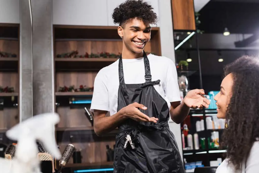 How Much Do You Tip a Hairdresser for a Haircut and More 3 A lady is having a discussion with a salon owner during the holiday season to determine how much is an appropriate holiday tip.