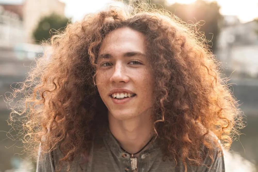 Wolf Cut: Men Hairstyle Tutorials with 9 Step-by-Step Videos 1 A young white male with curly, fine hair is wearing a shaggy wolf cut styled with texturizing spray on thicker hair.