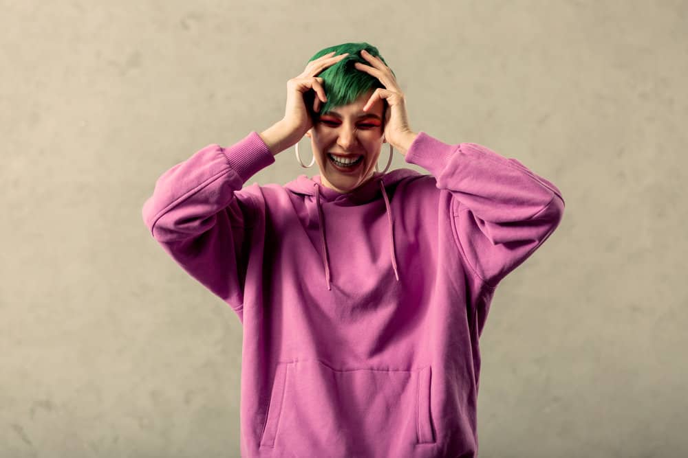 A happy female is wearing a purple hoodie after using dish soap and bath salts to remove green dye.