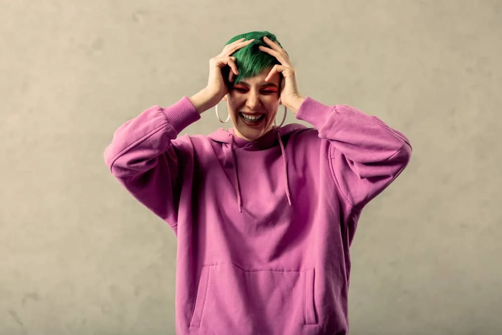 Fading Green Hair: How to Fade Green Dye Fast Step-By-Step 9 A happy female is wearing a purple hoodie after using dish soap and bath salts to remove green dye.