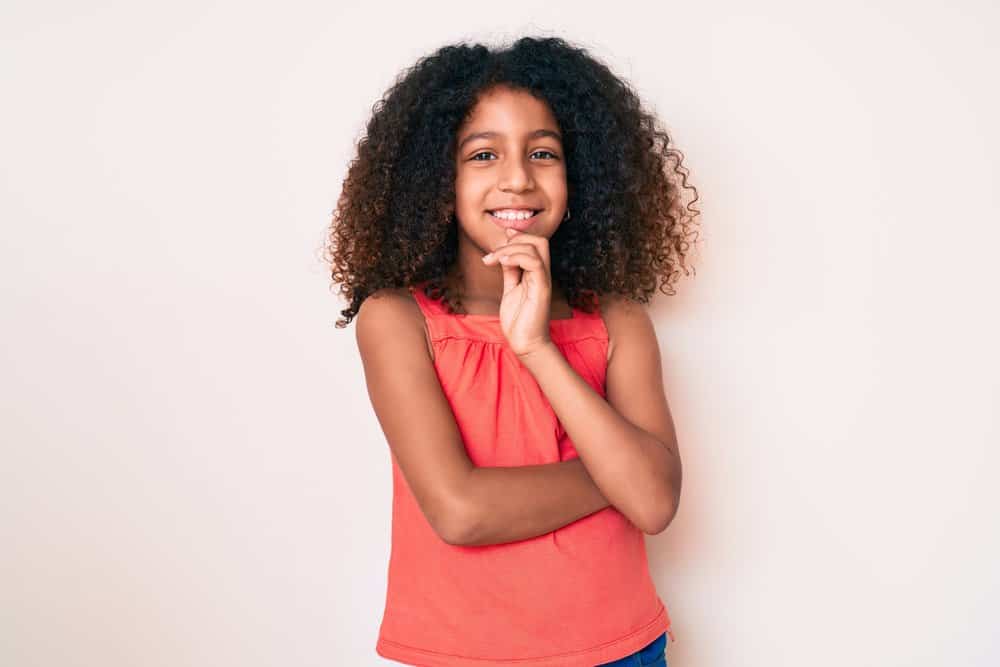 A little girl wearing curly natural hair in a wash-n-go hairstyle, which is a perfect hairstyle without any hair accessories.