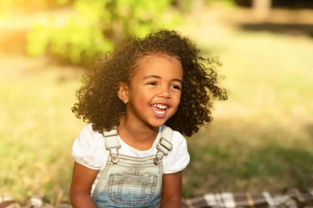 16 Cute and Easy Braided Bead Hairstyles for Toddlers 2 A cute young toddler female, after removing her kids' natural hair braids with purple beads, poses for a photo.