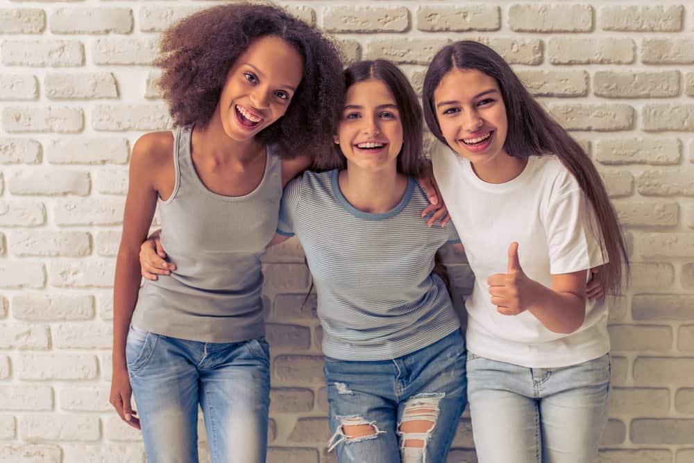 Three friends - one with natural curls following the big hair trend, one with long hair, and one with protective hair spray.