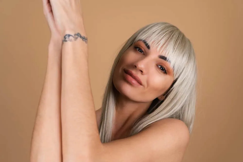 How Long Does It Take for Bangs to Grow Out Fully 7 A beautiful white woman with blonde hair color styled with essential oils and secured with bobby pins in the back.