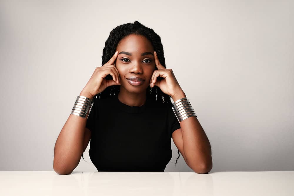 A black lady with beautiful curls, after using a small quantity of argan oil in new packaging, to give her hair more body.